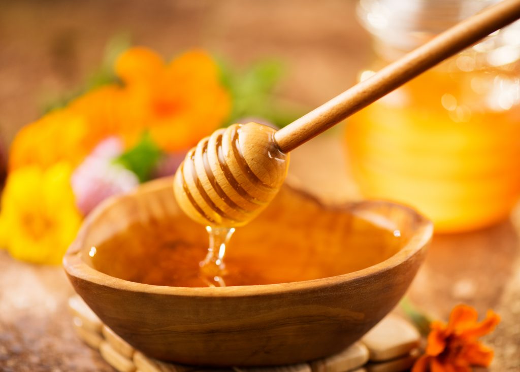 Honey,Dripping,From,Honey,Dipper,In,Wooden,Bowl.,Close-up.,Healthy